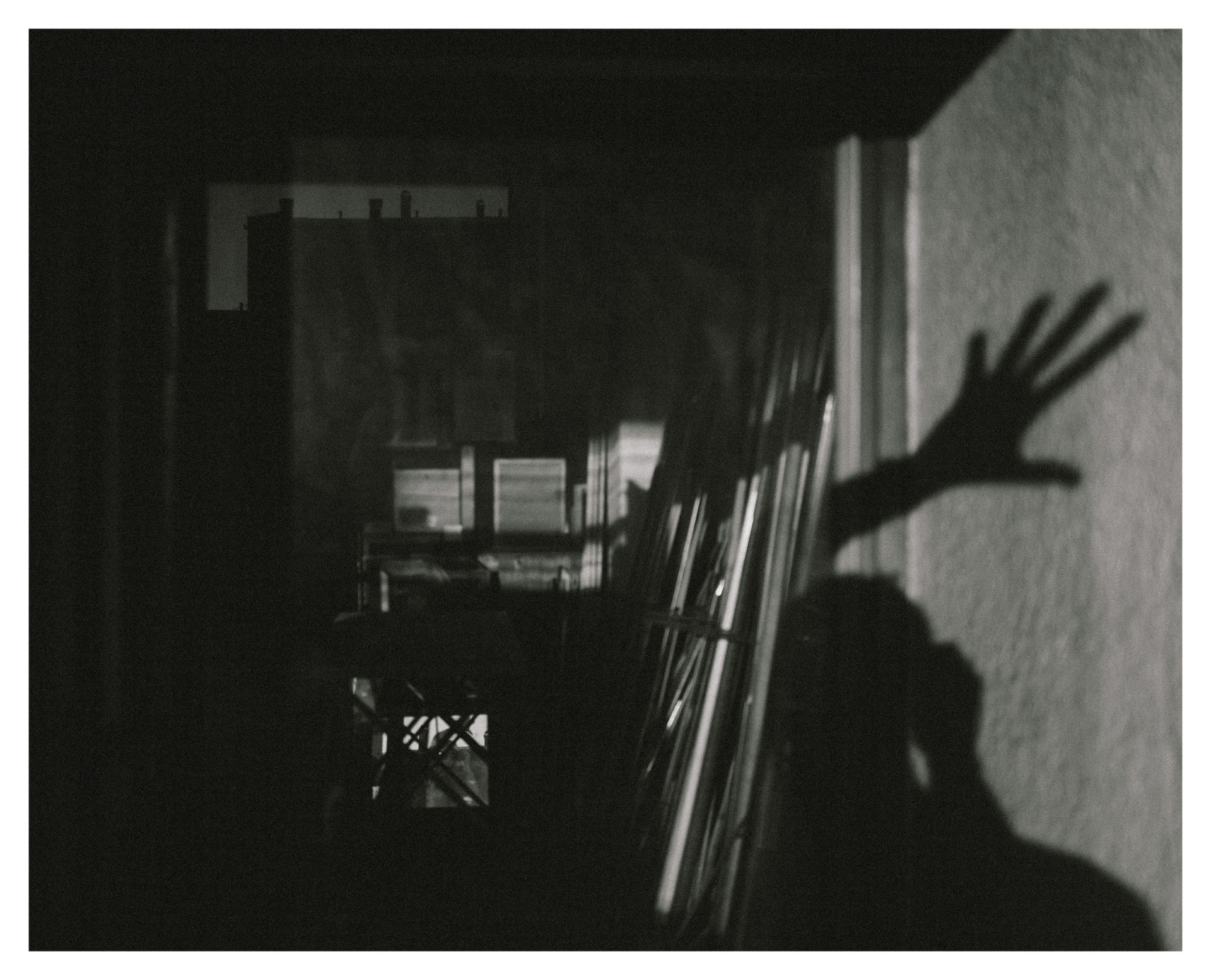 Shadow of an outstretched hand on a textured wall in a dark room